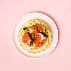 Delicious tart with fresh figs and pistachios on pink pastel backgrounds, top view