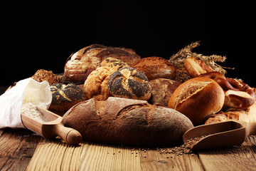 Different kinds of bread and bread rolls on board from above. Kitchen or bakery