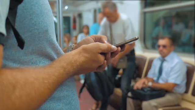 Casual traveler man reading from mobile phone smartphone writes messages screen while looks the navigator traveling on metro in the subway. slow motion video. Wireless internet on public transport