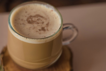 Сappuccino coffee in a glass mug on a wooden stand