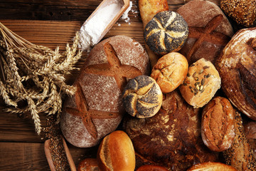 Different kinds of bread and bread rolls on board from above. Kitchen or bakery