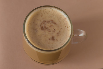Сappuccino coffee in a glass mug on a beige background