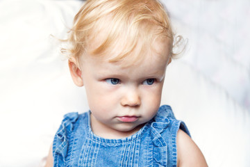 Naklejka premium portret curly-haired blue-eyed little baby girl in jeans clothes
