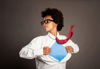 black woman opening her shirt like a superhero on a gray background