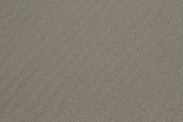 The background image of natural sea sand lies beautiful furrows. Background for a big board.