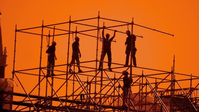 workers silhouette at sunset builders collect the design. construction workers concept building silhouette men lifestyle slow motion video group