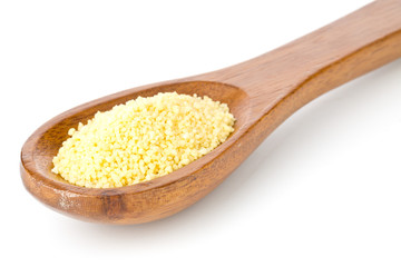 Heap of raw, uncooked couscous in wooden spoon over white