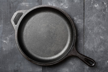 Empty, clean black cast iron pan or dutch oven top view from above on black table