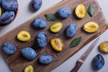 Fresh plums in bowl on wooden table
