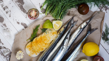 Garfish, billfish  raw and fresh, top view, with onions, lemon, prepared for cooking