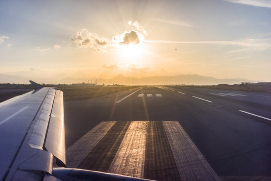 View of the wing of the aircraft from the porthole on the background of the runway