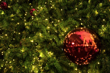 Close up background image of decorated outdoor Christmas tree with colorful lights and ornaments