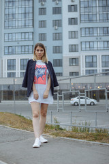 Fototapeta premium Beautiful woman with nude legs walking around city street wearing long white shirt
