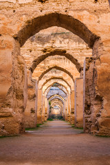 The ruined arches of the massive Royal Stables in the Imperial City of Meknes, Morocco - obrazy, fototapety, plakaty