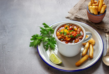 Chili con carne in gray mug. Stone background,selective focus.