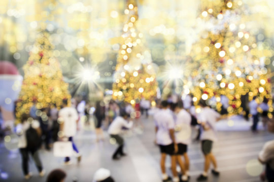 Blurry background image of defocused outdoor Christmas decorations with colorful lights and crowd of people in busy city street at night