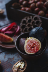 Fresh organic figs, nuts and autumn leaves on wooden board and dark stone table. Healthy lifestyle, seasonal fruit, sweet dessert, selective focus