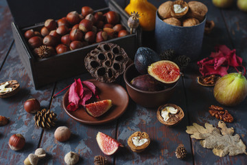 Fresh organic figs, nuts and autumn leaves on wooden board and dark stone table. Healthy lifestyle, seasonal fruit, sweet dessert, selective focus