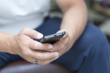 A man is sitting and reading an SMS on his mobile phone