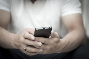 A man is sitting and reading an SMS on his mobile phone
