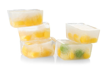 Corn grains and green peas in ice cubes on white background. Frozen vegetables