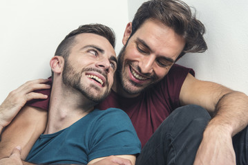 Happy gay couple embraced, joking and having fun in an intimate hug - obrazy, fototapety, plakaty