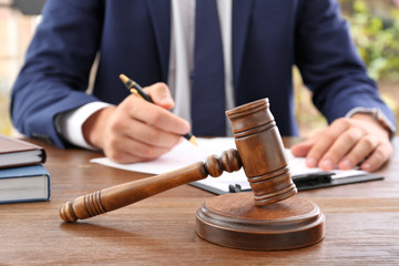 Gavel and blurred lawyer working with documents on background