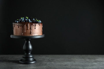 Fresh delicious homemade chocolate cake with berries on table against dark background. Space for text