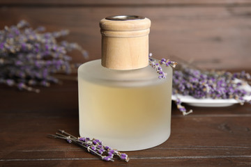 Bottle with aromatic lavender oil on wooden table