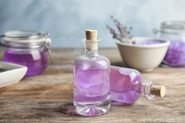 Bottles with natural lavender oil on table against blurred background