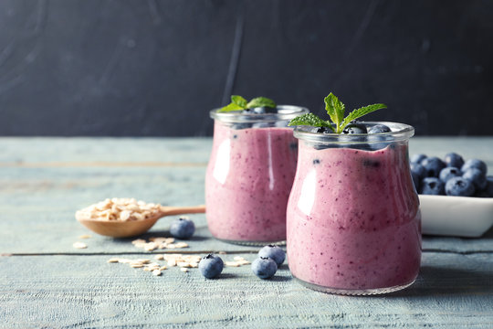 Tasty blueberry smoothie in jars, berries and oatmeal on wooden table