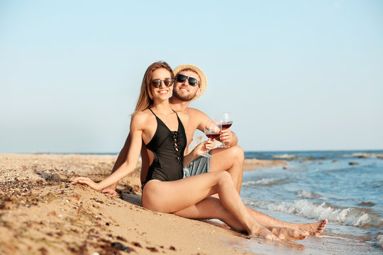 Young couple with glasses of wine on beach