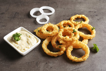 Homemade crunchy fried onion rings with sauce on color table