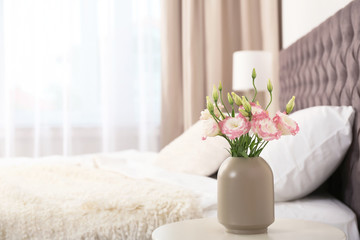 Beautiful flowers in vase and space for text on blurred background. Element of interior design