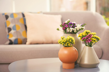 Beautiful flowers in vases as element of interior design on table. Space for text