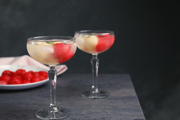 Glasses with tasty melon and watermelon ball drink on dark table. Space for text