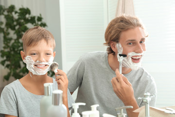 Father and son shaving together in bathroom