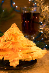 Edible Christmas tree made of puff pastry, mint tea in a glass, gold tinsel, vertical frame, wooden background.
