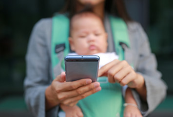 Close up business woman working by telephone with carrying her infant.