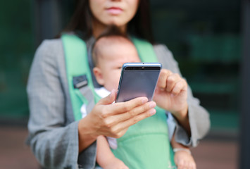 Close up business woman working by telephone with carrying her infant.