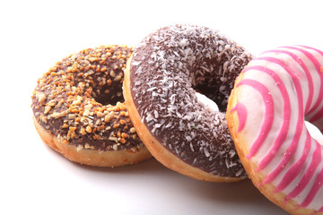 Assorted doughnuts in the glaze, colorful sprinkles and nuts on a white background.