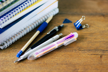 Stack of notebads and pens on wooden table