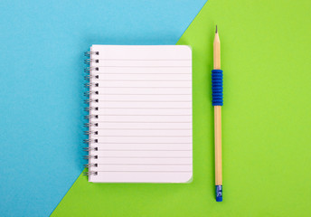 Spiral notepad and pencil on bright background.