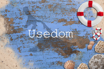 Maritime Dekoration auf blauem Holzuntergrund mit Umriß der Insel Usedom und Beschriftung 