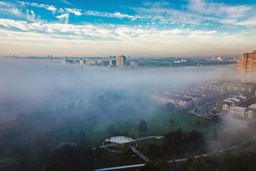 Foggy morning in Toronto city, Canada. Rays of early rising sun.  Landscape aerial top view with urban street covered with thick fog. Day white transparent mist in Canadian metropolia at sunrise.