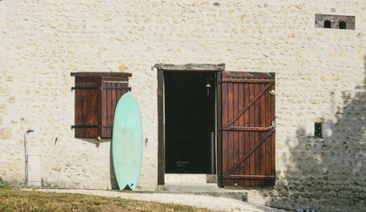 old house with surfboard standing beside