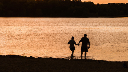 Fototapeta na wymiar People are having fun at a lake under sunset