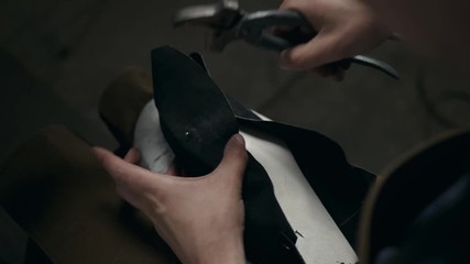 workers using a handtool to working on shoe component in footwear factory leather shoemaker