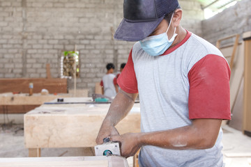 worker cutting the edge of wood board using fret saw