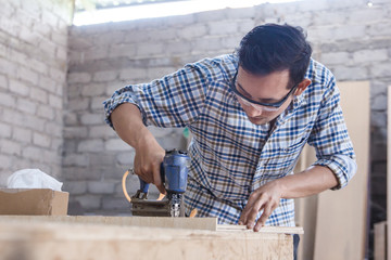 worker at carpenter workspace installing nail using pneumatic na